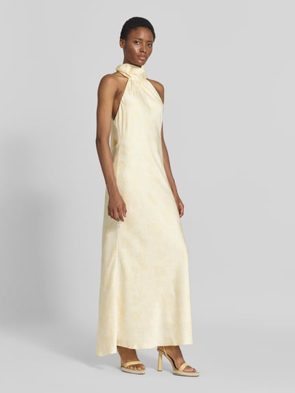 Frauenmodel trägt Abendkleid mit Neckholder Modell 'Fiona' von Neo Noir in Creme, Satin, taillierte Passform, Maxilänge, Ganzkörperansicht von vorne.