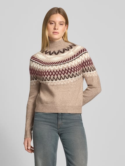 Frauenmodel trägt Pullover mit Jacquardpasse Modell 'VMMAPLE' von VERO MODA, mehrfarbig, geometrisches Rautenmuster, Strickoptik, Mock Neck, hochgeschlossen, Langarm, gerippte Abschlüsse, Ganzkörperansicht von vorne.