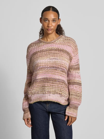 Frauenmodel trägt Strickpullover mit Rundhalsausschnitt Modell 'SIMONE' von JJXX, grob gestrickt, rosa und braune Streifen, Loose Fit, Ganzkörperansicht von vorne, Damen Strickpullover Kontext integriert.