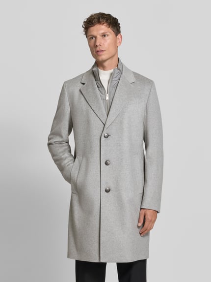 Männermodel trägt Mantel aus Wolle Kaschmir mit Westeneinsatz von BOSS in Hellgrau, einreihig, strukturierte Optik, Longline, Ganzkörperansicht von vorne.