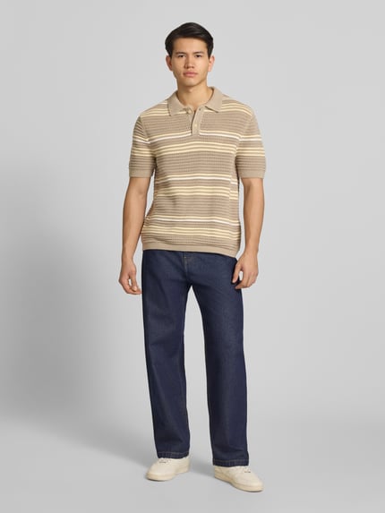 Männermodel trägt relaxed fit heren poloshirt aus zuiver katoen Modell 'LAGUNA' von Levi's® in gebreide look met streepmotief, labelpatch, polokraag, V-hals, korte knoopsluiting, korte mouw met geribde boorden, rompzoom geribd, materiaalverwerking knitwear, kleur beige en crèmetinten, Ganzkörperansicht von vorne.