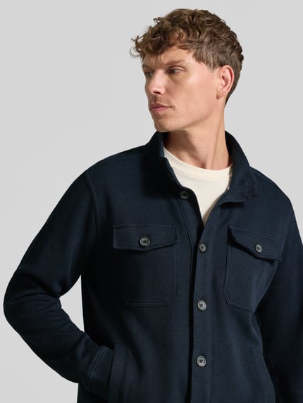 Männermodel trägt Regular Fit Jacke aus Baumwoll-Mix Modell 'SELANIK' von LERROS, dunkelblau, sichtbare Brusttaschen, Nahaufnahme Oberkörper.