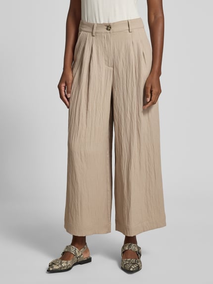Frauenmodel trägt Culotte mit Knopf- und Reißverschluss Modell 'Milo' von LOLLYS LAUNDRY im Wide-Fit aus Material-Mix mit Viskose-Anteil, beige Textur, seitliche Eingrifftaschen, Bundweite 37 cm, Innenbeinlänge 68 cm, Ganzkörperansicht von vorne.