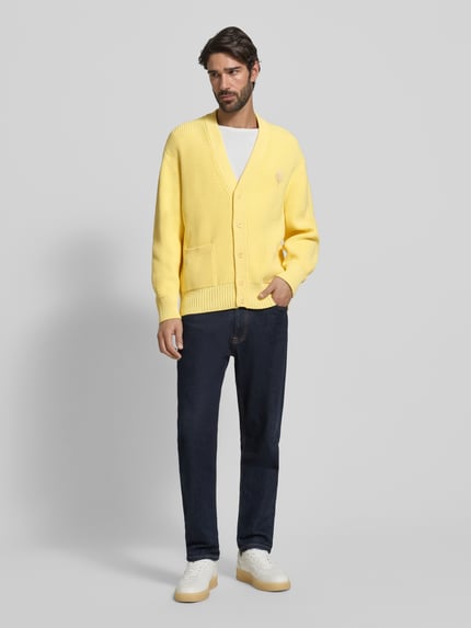 Mannelijk model draagt Relaxed Fit Gebreid jack uit katoenmix Model 'COTES PERLEES' van Lacoste, look: effen geel, knoopsluiting, labelopschrift, labelstitching, crew neck, diepe V-hals, lange mouw met geribde mouwboorden, geribde rompzoom, materiaalverwerking: knitwear, katoenmix. Volledige lichaamsopname van voren.