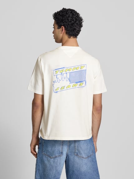 Männermodel trägt Regular Fit T-Shirt aus reiner Baumwolle Modell '90s' von Tommy Jeans, unifarben, Label Print, Rückansicht.