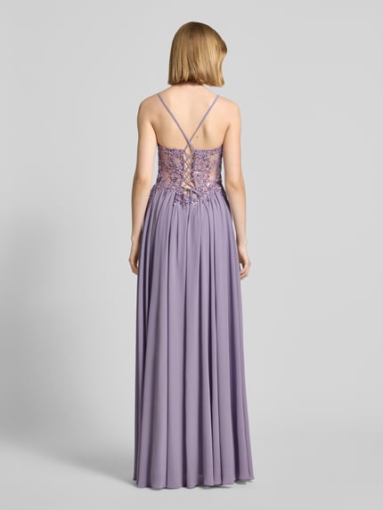 Frauenmodel trägt Abendkleid mit Spitze und Strasssteinbesatz von Mascara aus fliederfarbenem Chiffon, A-Linie, Maxikleid, V-Ausschnitt, rückseitig überkreuzte Spaghettiträger, Rückseitige Schnürung, Haken- und Reißverschluss, Rückenlänge 132 cm, Brustweite 40 cm, Ganzkörperansicht Rückansicht.