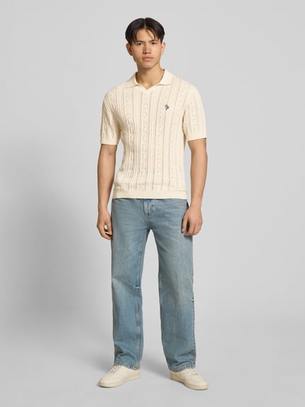 Männermodel trägt Slim Fit Strick-Poloshirt mit Label-Stitching von REVIEW in Creme mit Zopfmuster, Reine Baumwolle, Ganzkörperansicht von vorne.
