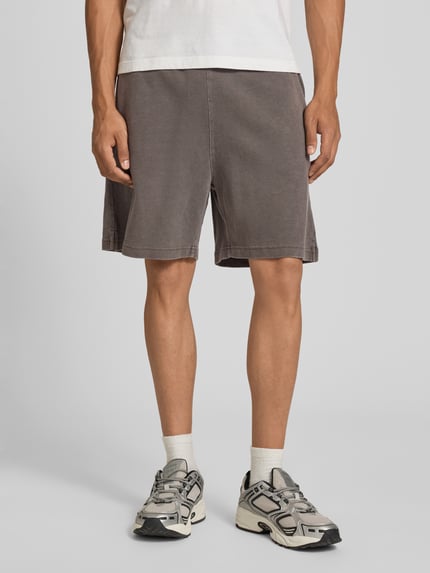 Männermodel trägt Regular Fit Shorts mit elastischem Bund Modell 'Harper' von Carhartt Work In Progress in Braun aus reiner gewachster Baumwolle, Nahaufnahme Oberschenkel, Kontext: Herren Shorts, Bundweite 44 cm, Innenbeinlänge 17 cm, Größe M.