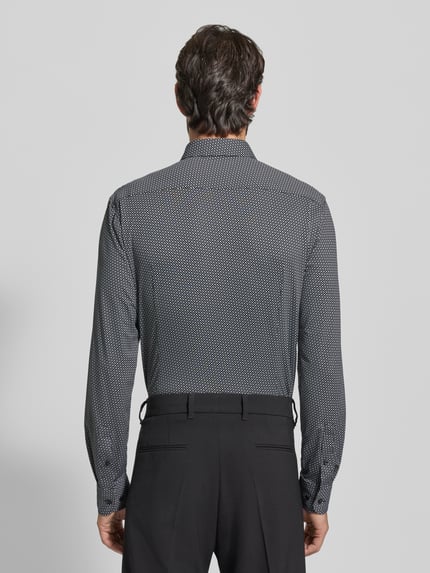 Männermodel trägt Slim Fit Freizeithemd mit Allover-Muster Modell 'HANK' von BOSS, abstraktes Muster, Kentkragen, Ganzkörperansicht Rückansicht.