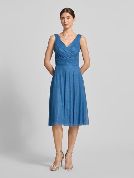 Modelka kobieca nosi Knielanges Cocktailkleid mit V-Ausschnitt od TROYDEN COLLECTION, niebieski szyfon, krój slim fit, szerokie ramiączka, długość do kolan, dekolt i tylny dekolt w szpic, tylny zamek, szerokość w rozmiarze 36: 43 cm, długość pleców w rozmiarze 36: 85 cm, widok całej sylwetki z przodu
