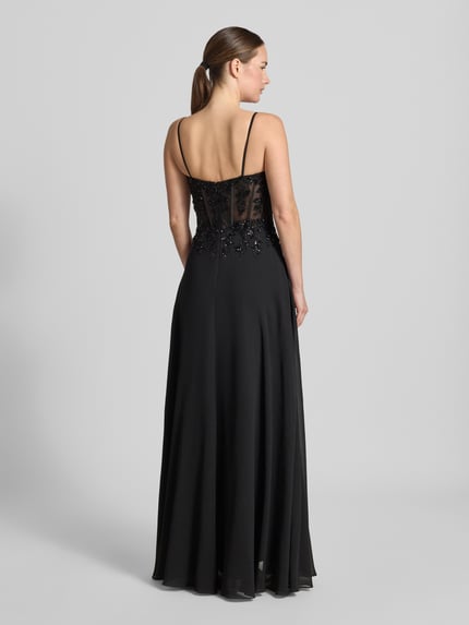 Frauenmodel trägt Abendkleid mit Pailettenbesatz von Mascara, czarna, cekinowe obszycie, taliowany krój, kwiatowy wzór, półprzezroczysty materiał, cienkie ramiączka, Długość tyłu w rozmiarze 36: 131 cm, Szerokość w rozmiarze 36: 39 cm, widok całej sylwetki z tyłu