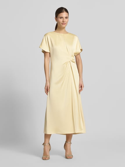 Frauenmodel trägt Cocktailkleid mit Raffung und Kappärmeln von Christian Berg Cocktail in Creme, Midikleid aus Viskose-Mix, taillierter Schnitt, Ganzkörperansicht von vorne.
