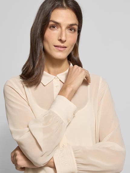 Modelka kobieca nosi Regular Fit Bluse in semitransparenter Optik von JOOP!, kremowa, z kołnierzykiem i guzikami, materiał z domieszką stretchu, półprzezroczysta, Nahaufnahme górnej części ciała.