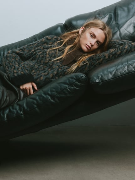 Frauenmodel trägt Relaxed Fit Pullover mit Alpaka-Anteil in Strick-Optik von MYON, Animal-Print in dunklen Tönen, Nahaufnahme Oberkörper. Elastischer Baumwoll-Mix, Rundhalsausschnitt.