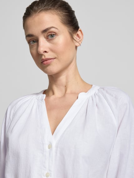 Vrouwenmodel draagt Relaxed Fit Hemdbluse Leinen-Baumwoll-Mix Modell 'ALBERTA' van Selected Femme, wit met V-hals, eenrijige knoopsluiting, 3/4-mouwen, unicolor, meerkleurig, gestreept patroon, elastische mouwafsluiting, afgeronde zoom, materiaalmix, close-up bovenlichaam.