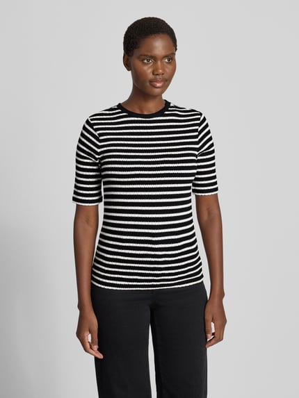 Vrouwenmodel draagt t-shirt met halflange mouwen van Christian Berg Woman, viscosemix met stretch, recht model, ronde hals, ruglengte maat S 58 cm, zwart-wit gestreept patroon, textuur met zichtbare structuur, geheelvooraanzicht.