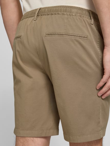 Männermodel trägt Straight Fit Shorts mit Bundfalten von Profuomo in Beige, elastischer Bund, Eingrifftaschen, Nahaufnahme Rückansicht.