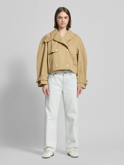 Vrouwenmodel draagt trenchcoat met mouwsluitingen model 'MIA' van Topshop, puur katoen, regular fit, platte kraag, knoopsluiting, met dubbele rij knopen, zandkleur, textuur glad, lengte tot heup, zichtbare details en naden, dames, Ganzkörperansicht von vorne.
