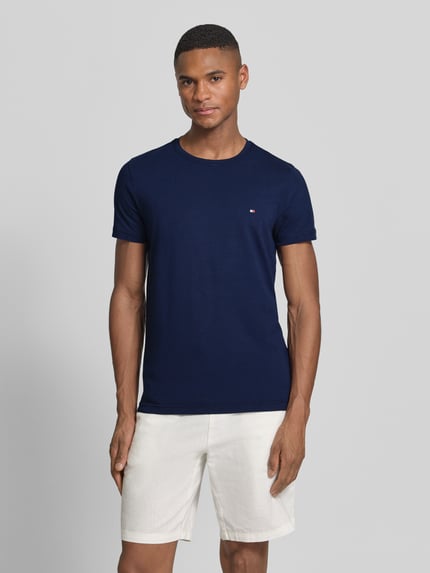Mannelijk model draagt Slim Fit T-Shirt aus Baumwoll-Mix van Tommy Hilfiger, donkerblauw, uni, ronde hals, korte mouwen, logo detail, stretch katoenmix, vooraanzicht volledige lichaamsopname