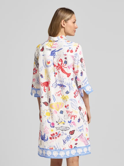 Modelka kobieca nosi kolorowe, białe knielanges Hemdkleid aus Leinen mit Hemdblusenkragen von Christian Berg Woman, prosty krój, długość do kolan, kołnierz koszulowy, krótka zakryta listwa guzikowa, rękaw 3/4, długość tyłu w rozmiarze 36: 97 cm, szerokość w rozmiarze 36: 44 cm, długość rękawa w rozmiarze 36: 41 cm, wzory motywy, widok całej sylwetki z tyłu