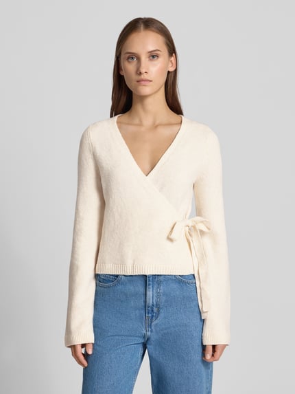 Frauenmodel trägt Strick-Cardigan in Wickeloptik von REVIEW in Creme, Regular Fit, V-Ausschnitt, Material-Mix mit Stretch, Ganzkörperansicht von vorne.