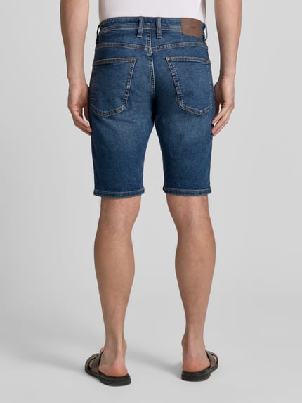 Männermodel trägt Regular Fit Jeans-Bermudas aus Baumwoll-Mix von s.Oliver RED LABEL, 5-Pocket-Design, Kontrastnähte, Ganzkörperansicht Rückansicht.