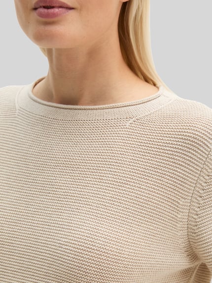 Kobieta nosi Regular Fit Pullover aus reiner Baumwolle od MARC O'POLO, kolor jednolity, dzianinowa faktura, długi rękaw, dekolt łódka, boczne kieszenie, tunelowy dół, materiał: czysta bawełna, zbliżenie na górną część ciała.