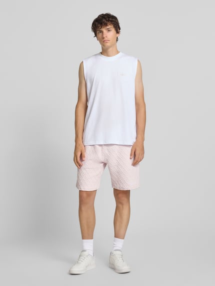Männermodel trägt Relaxed Fit Sweatshorts mit Strukturmuster Modell 'Jovren' von Pegador in Hellrosa, Ganzkörperansicht von vorne. Herren Sweatshorts aus elastischem Material-Mix mit Baumwoll-Anteil, Bundweite 39 cm, Innenbeinlänge 24 cm.