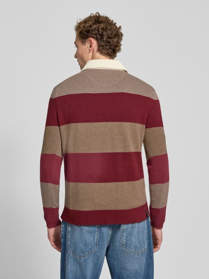 Männermodel trägt Regular Fit Pullover aus reiner Baumwolle von GANT in Rot und Braun mit breiten Streifen, Ganzkörperansicht Rückansicht.