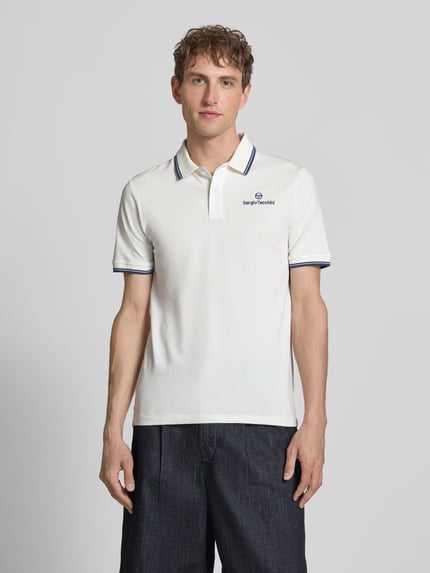 Männermodel trägt Slim Fit Poloshirt mit Logo-Stitching Modell 'Reed' von SERGIO TACCHINI, weiß mit blauen Details, Ganzkörperansicht von vorne. Elastischer Baumwoll-Mix, kurzärmeliges Design, Polokragen, Rückenlänge bei Größe M: 71 cm.