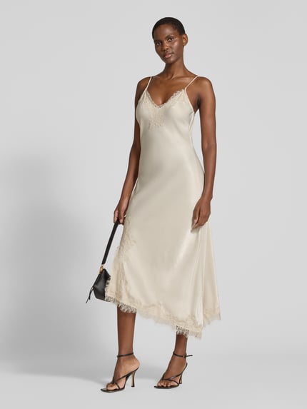 Frauenmodel trägt Maxikleid mit Spitzenbesatz von VERO MODA in glänzendem Unifarbton mit Spitze, V-Ausschnitt, Ganzkörperansicht von vorne.