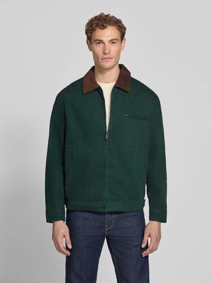 Männermodel trägt Regular Fit Jacke aus reiner Baumwolle von MCNEAL in Dunkelgrün mit braunem Cord-Kragen, Reißverschluss, Nahaufnahme Oberkörper. Rückenlänge bei Größe M: 69 cm, Brust- und Eingrifftaschen.