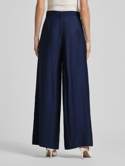 Frauenmodel trägt Wide Leg Stoffhose aus Viskose-Mix Modell 'FINJA' von GUIDO MARIA KRETSCHMER WOMAN, dunkelblau, feine Struktur, Falten, Ziertasche am Gesäß, Ganzkörperansicht Rückansicht.