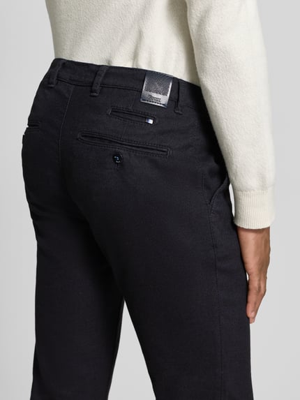 Männermodel trägt schwarze Stoffhose mit französischen Eingrifftaschen Modell 'Fabio' von Brax, reine Baumwolle, Gerader-Schnitt, Detailaufnahme Rückansicht.