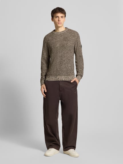 Männermodel trägt Strickpullover mit gerippten Abschlüssen Modell 'LIAM' von Jack & Jones in Beige-Braun-Melange, Regular Fit, Baumwoll-Mix, Rundhalsausschnitt, Ganzkörperansicht von vorne.