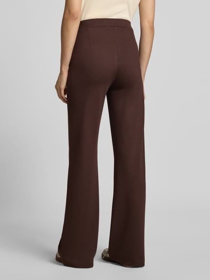 Frauenmodel trägt Straight Fit Stoffhose mit Viskose-Anteil von Smith and Soul, dunkelbraun, mit Bundfalten und Eingrifftaschen, Ganzkörperansicht Rückansicht.