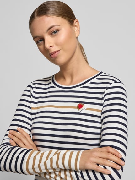 Vrouwenmodel draagt Longsleeve met Label-Detail van Marc Cain in slim fit, gestreept katoen-elastaan, geribde ronde hals, detailopname bovenlichaam.