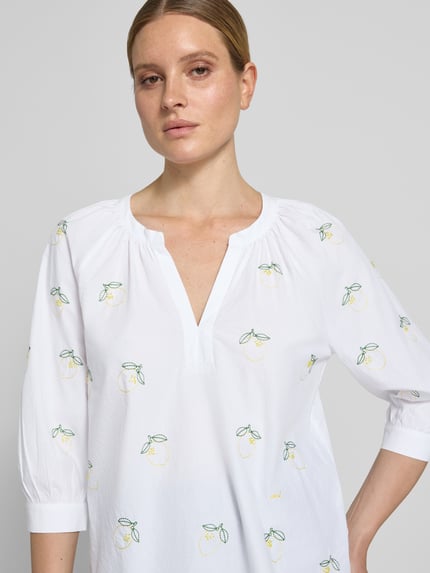 Kobiece model prezentuje Regular Fit Tunikabluse mit Stitchings und 3/4-Arm od Oui, biała bawełna, hafty, wzór na całej powierzchni, dekolt w serek, rękaw o dł. 3/4, długość tyłu w rozmiarze 36: 66 cm, długość rękawów w rozmiarze 36: 39 cm, zbliżenie na górną część ciała