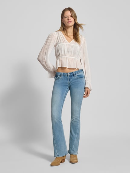 Vrouwenmodel draagt Low Rise Flared Jeans met steekzakken model 'JOEY' van TRUE RELIGION in used-look, lichtblauwe kleur, hele lichaam vooraanzicht.