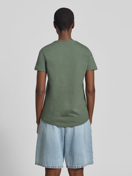 Kobiece modelka nosi damski t-shirt Regular Fit T-Shirt aus reiner Baumwolle Modell 'MIRANDA' od Vero Moda, efekt: jednolity kolor, krój regular fit, aplikacja: haft angielski, okrągły dekolt, krótki rękaw, wykończenie materiału: dżersej, materiał: czysta bawełna, widok całej sylwetki z tyłu.