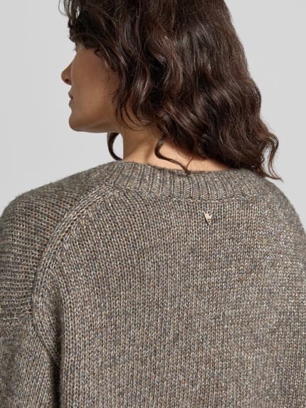 Frauenmodel trägt Oversized Strickpullover mit Woll-Anteil Modell 'Welma' von MOS MOSH in Grau-Melange, strukturierte Textur, Detailaufnahme Rücken, KI-modifiziertes Bild.
