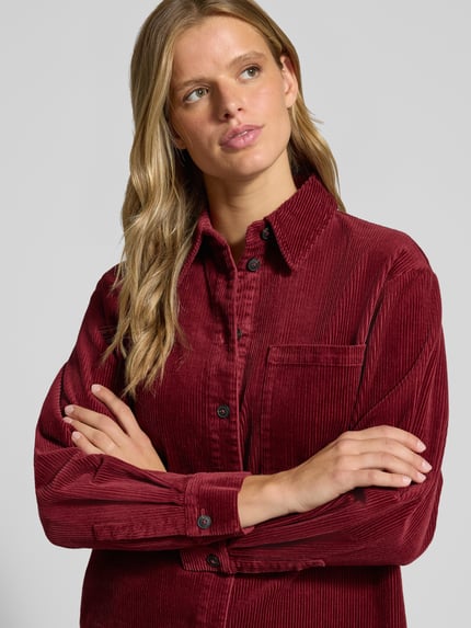 Frauenmodel trägt Relaxed Fit Langarmbluse aus Baumwoll-Mix von Marc O'Polo DENIM in dunklem Rot mit Cordstruktur, Nahaufnahme Oberkörper.