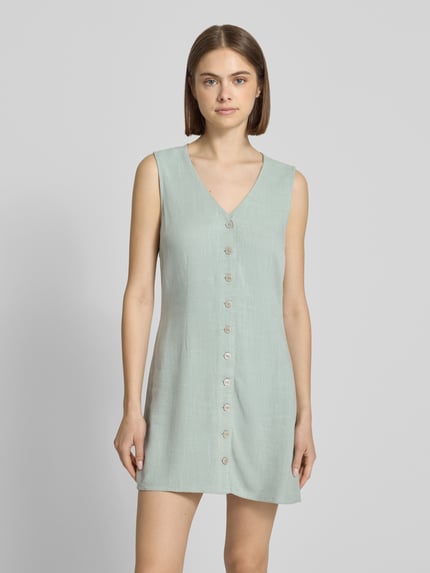 Vrouwenmodel draagt vrijetijdsjurk van model 'SIESTA' van Only, look: effen, getailleerd, minilengte, V-hals, knoopsluiting, mouwloos, materiaalverwerking: gevlamd garen, materiaal: mix van viscose en linnen, Ganzkörperansicht van voren.