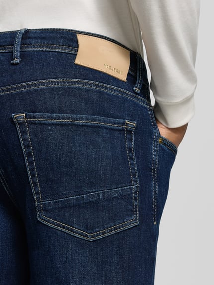 Männermodel trägt Slim Fit Jeans mit Dark-Wash-Optik Modell 'Arne' von MAC, Denim, 5-Pocket-Design, Nahaufnahme Rückansicht.
