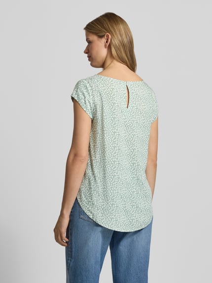Kobiece modelka nosi Regular Fit Blusenshirt aus reiner Viskose Modell 'NOVA' od Only, jasnozielony z białym wzorem, krótki rękaw, dekolt okrągły, zaokrąglony dół, detal z tyłu, krój regular fit, tylny wycięcie typu łezka, widok całej sylwetki z tyłu.