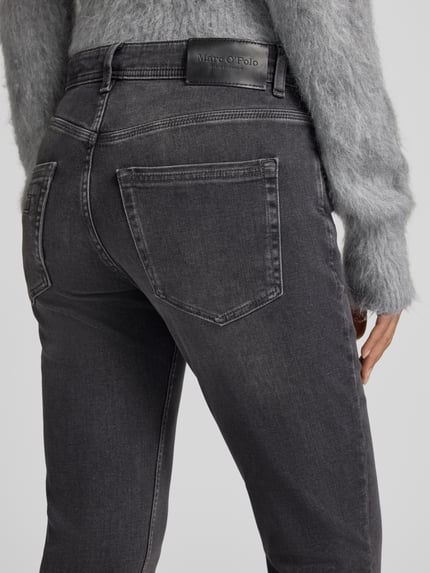Frauenmodel trägt Mid Waist Straight Fit Jeans mit Knopfleiste von Marc O'Polo, Medium Wash, Faded, Denim, Used Look, Nahaufnahme Rückansicht.