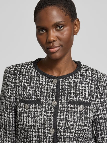 Modelka nosi Slim Fit Blazer in Bouclé-Optik Model 'JOLE' von GUESS, Mieszanka materiałów z dodatkiem wiskozy, imitacja bouclé, listwa guzikowa na całej długości, kieszenie na piersi, zbliżenie na górną część sylwetki.