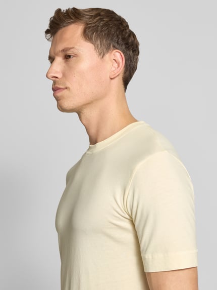 Männermodel trägt T-Shirt mit geripptem Rundhalsausschnitt von Drykorn aus reiner Baumwolle in Creme, Regular Fit, Nahaufnahme Oberkörper.