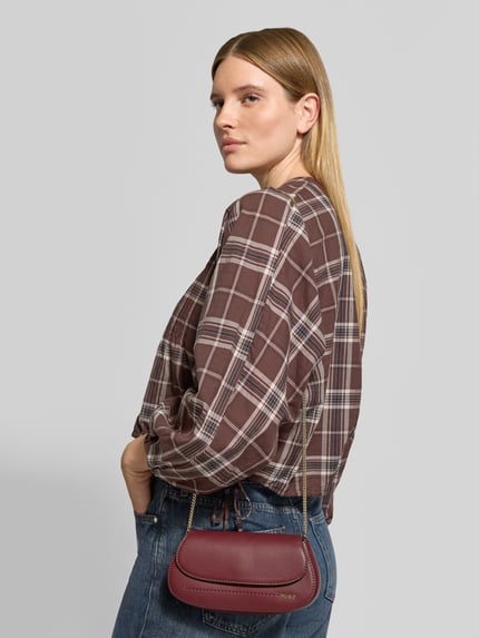 Frauenmodel trägt Clutch mit Schulterkette Modell 'Yorih_Clutch' von HUGO in Unifarbe mit Struktur, Logo-Schriftzug, Kettenriemen, Ganzkörperansicht Rückansicht.