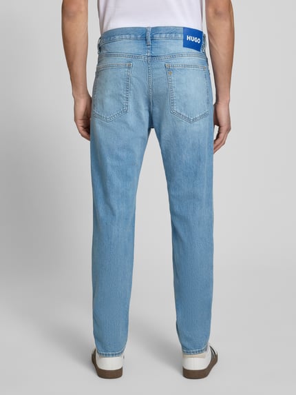 Mężczyzna nosi Straight Fit Jeans aus Baumwolle von HUGO Blue, jasnoniebieski, jednokolorowy, 5 kieszeni, detal z logo, średni stan, krój straight fit, widok całej sylwetki od tyłu.